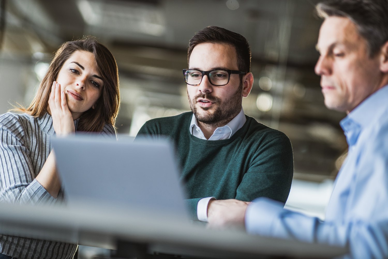 Young couple and real estate agent using laptop on a meeting in the office. Young couple using computer with their insurance agent on a meeting in the office.